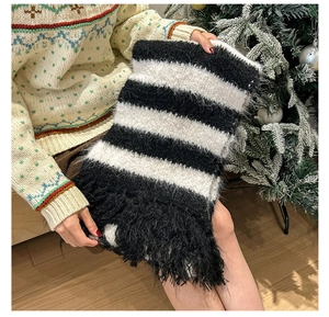 Close-up of black and white striped knit scarf with long fringe details and fuzzy texture