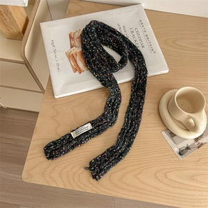 Black knit confetti scarf with colorful speckled wool dots on a minimalist wooden table