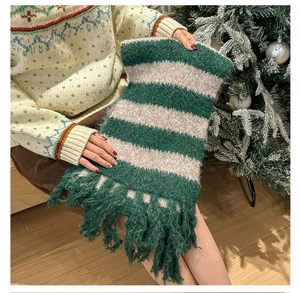Detail of green and white striped knit scarf with long tassels in a Christmas setting