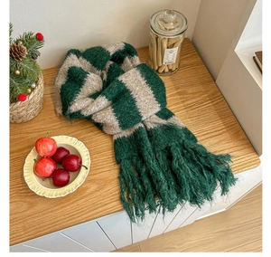 Close-up of thick knit striped winter scarf with fringe in festive Christmas setting