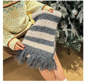 Detail view of plush striped winter scarf with thick tassels in blue and beige