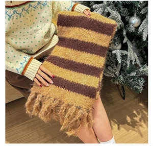 Detail of yellow and brown striped knitted winter scarf with soft decorative tassels