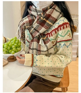 Detail of soft knit Fair Isle sweater texture with colorful wave patterns and plaid scarf