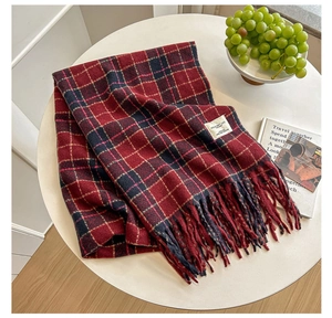 Detail of red and navy plaid scarf with soft fringe and white woven brand label