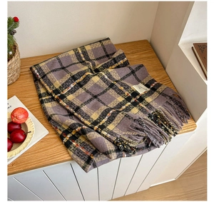Detailed close-up of plaid scarf with soft tassels on a warm wooden background