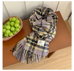 Detail of purple plaid knit scarf featuring classic fringe and brand label on leather