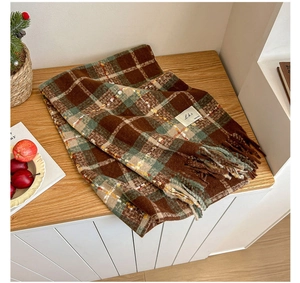 Detail of plaid scarf texture with tassels and logo label on a wooden surface