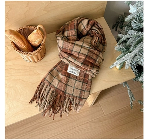 Detail of vintage plaid scarf with soft fringe on a wooden table with winter decor