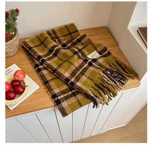 Detailed view of checkered scarf with fringe tassels and label on wooden surface