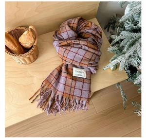 Close-up of retro plaid scarf with fringes and white label on a cozy wooden table