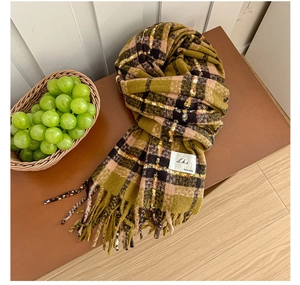 Detailed view of soft plaid scarf with fringe and classic woven label on a wooden bench