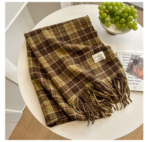 Close-up of retro plaid scarf with fringes and white label on a white table background