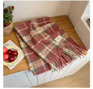 Detailed view of pink and brown plaid scarf featuring soft tassels and sewn-on label