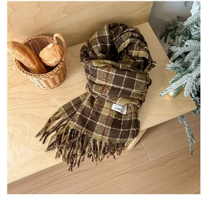 Macro detail of vintage plaid scarf texture with fringes and woven label on a wooden bench