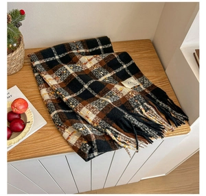 Detail of a thick plaid scarf with classic tassels on a cozy wooden tabletop setting