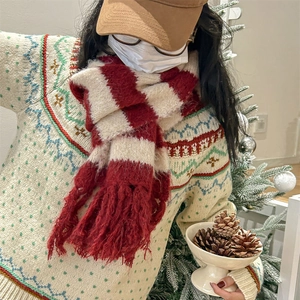 Winter red and beige striped knit scarf with thick tassels worn by a model in a cozy room