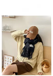 Detail of dark blue plaid fringe scarf paired with a brown Malibu embroidery baseball cap
