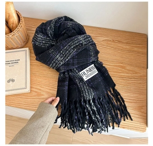 Detailed view of thick checkered scarf with long tassels on a cozy wooden desk