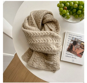 Detailed cable knit texture of beige scarf with vegetable label on a minimalist table