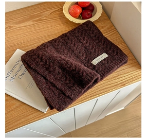 Detail shot of chunky cable knit scarf in burgundy with a branded woven label