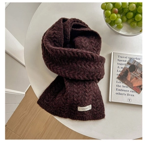 Macro shot of dark burgundy knitted scarf with herringbone texture and white brand tag