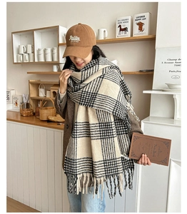 Close-up of beige houndstooth scarf showing thick cashmere-like texture and tassel detail