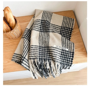 Macro shot of soft beige and black houndstooth scarf with elegant fringe detail