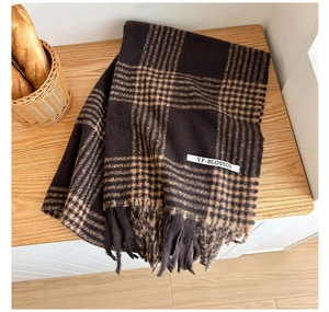 Detailed view of soft brown houndstooth scarf with elegant fringes on wooden background