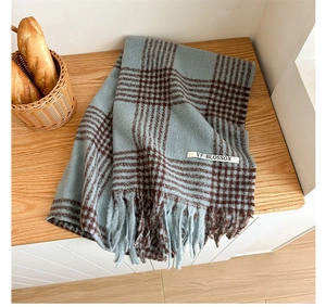 Detailed close-up of blue and brown houndstooth scarf with soft fringe and logo tag