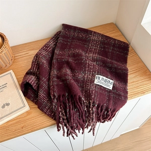 Cozy wine red plaid scarf with tassels on wooden table for a warm winter aesthetic