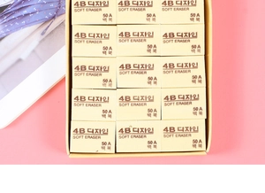 Detail view of large 4B soft erasers neatly organized in a yellow box on pink background
