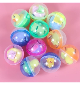 Gros plan de jouets en capsule colorés avec mini voitures et animaux sur fond rose