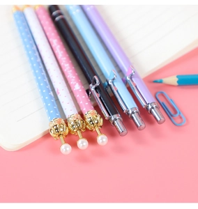 Close-up of colorful mechanical pencils with crown pendants on an open notebook