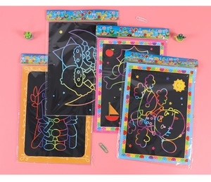 Close-up of DIY rainbow scratch art cards for kids with astronaut and sailboat designs