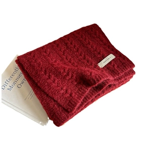 Burgundy cable knit wool scarf with a vegetable label on a minimalist white background