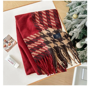 Détail d'une écharpe d'hiver pied-de-poule rouge avec franges et étiquette de marque