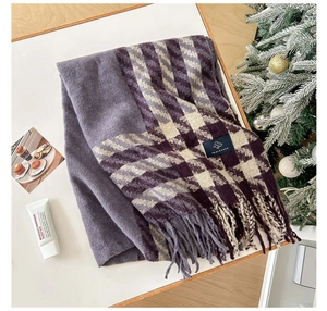 Détail d'une écharpe pied-de-poule violette et beige avec franges dans un décor d'hiver