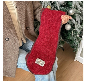 Détail d'une écharpe en tricot rouge avec étiquette tissée vintage et bordure brodée