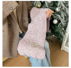 Gros plan sur l'écharpe en maille rose avec bords surjetés et étiquette décorative