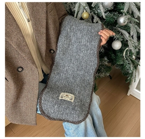 Détail d'une écharpe en tricot gris foncé avec étiquette vintage et bords cousus main