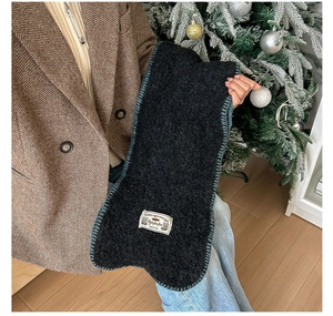 Vue détaillée d'une écharpe en tricot noir avec écusson blanc et couture vintage