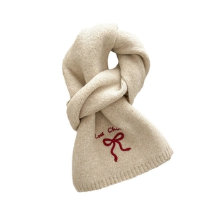 Beige gebreide sjaal met rood geborduurd strikje en zachte wollen wintertextuur