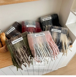 Close-up of multicolored plaid mohair scarves with fringe and brand label on wooden shelf
