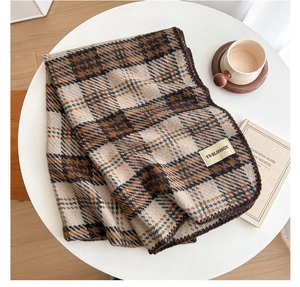 Detail of plaid scarf featuring brown lock-stitch edges and woven brand label