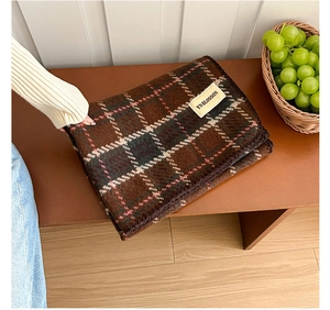 Close-up of soft plaid scarf fabric with stitched brand label and vintage texture