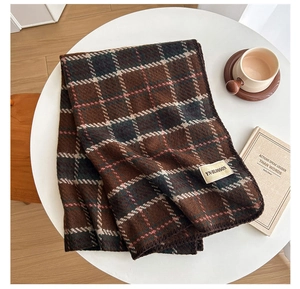 Detail of dark brown and green plaid scarf with refined overlock stitching and brand label