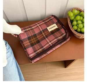 Close-up of pink and brown plaid cashmere scarf with stitched edge on wooden bench