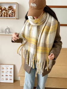 Détail d'une écharpe d'hiver à carreaux jaune et beige avec de longues franges