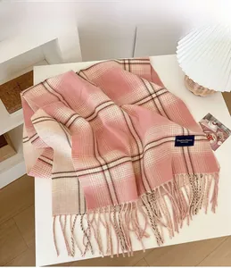 Detail of soft pink plaid scarf with elegant woven label and delicate tassel edges