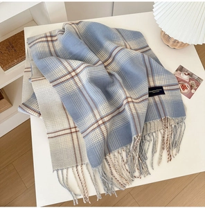 Detailed view of light blue plaid scarf with long fringe and elegant woven label